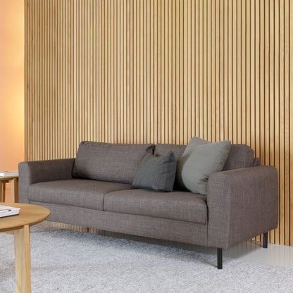 Gray sofa with cushions against a wooden paneled wall.