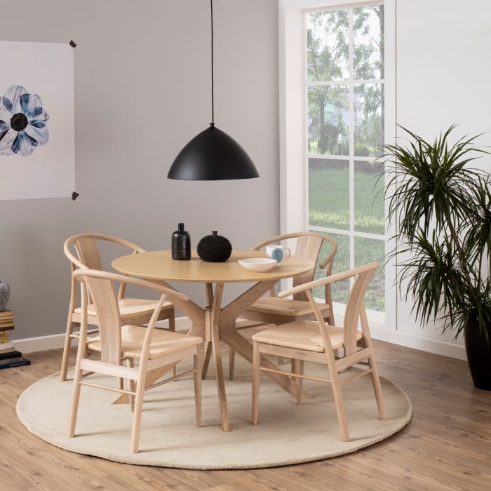 Dining area with wooden table and chairs in a room with large windows and a plant.