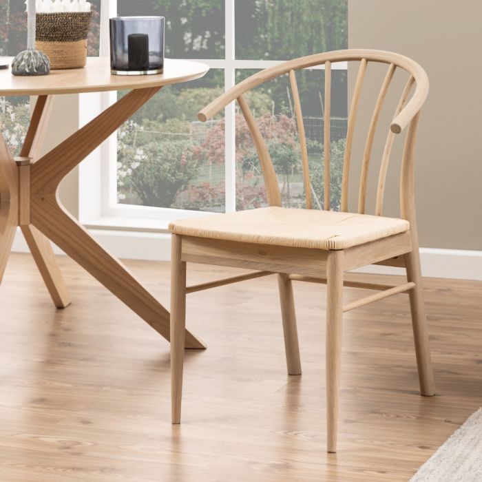 Wooden chair and dining table in a room with large windows.