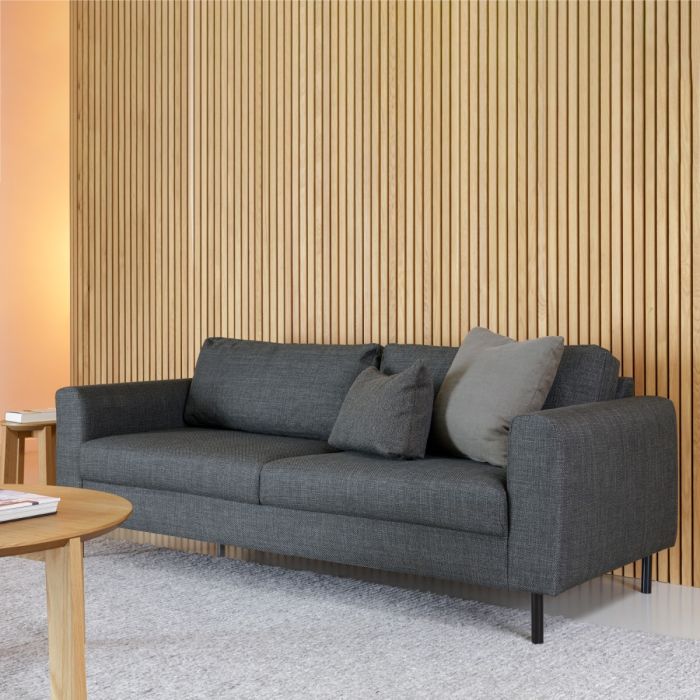 Gray sofa with cushions in a room with wooden wall paneling