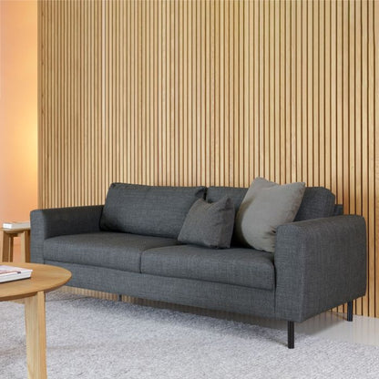 Gray sofa with cushions in a room with wooden wall paneling