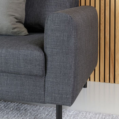 Gray upholstered chair with wooden slat wall in the background