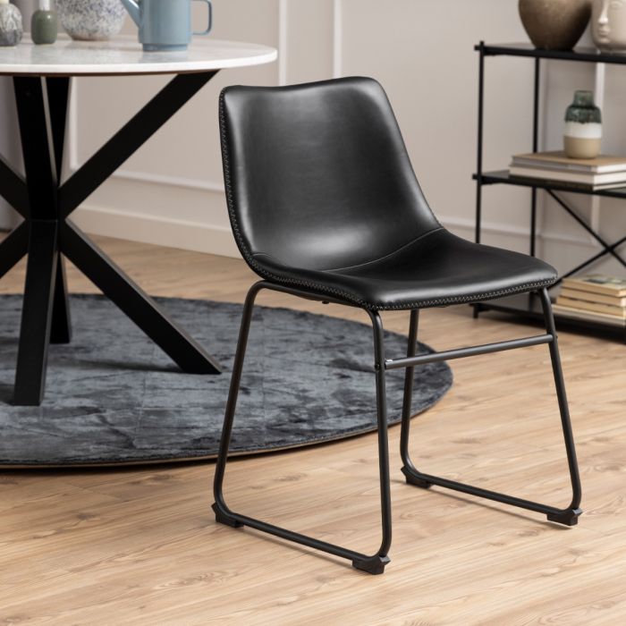 Black leather chair in a room with a table and shelves.