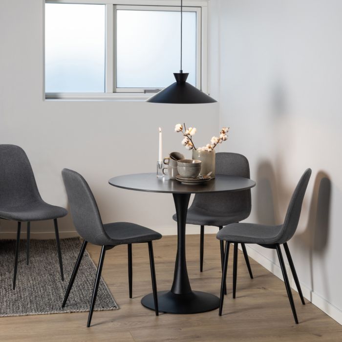 Dining area with a round black table and four gray chairs in a room with a window.