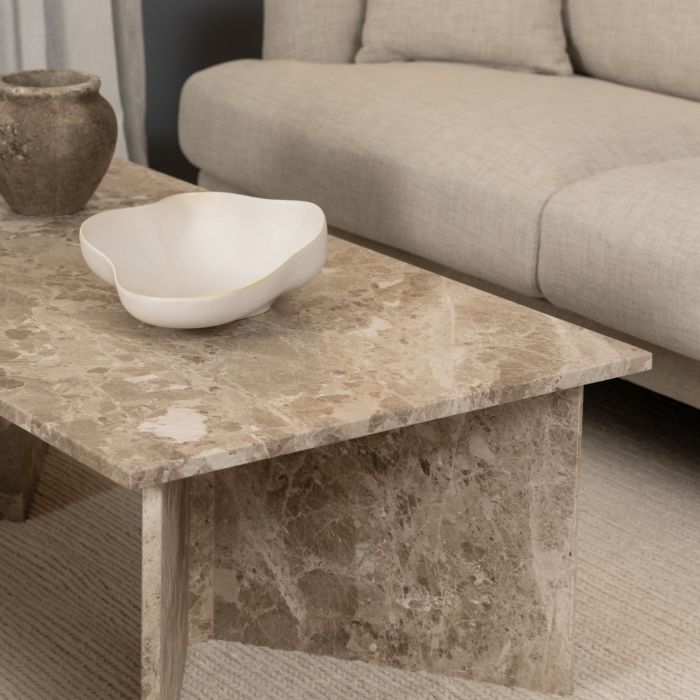 Marble coffee table with a white bowl and a textured vase in a living room setting.