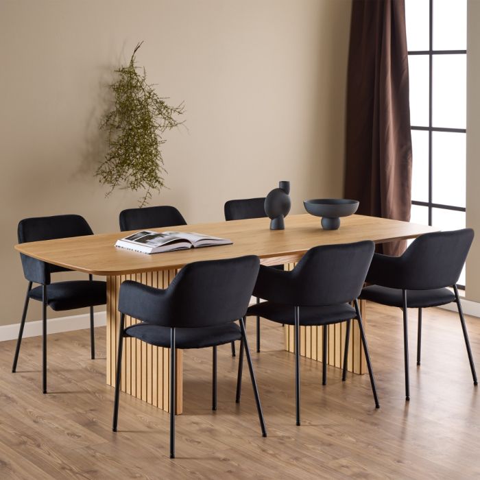 Dining room with wooden table and black chairs against a beige wall.