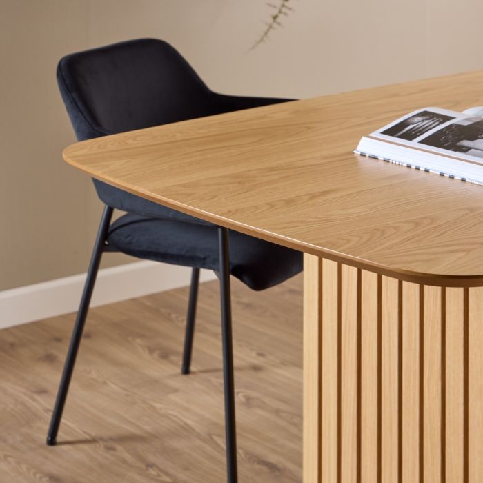 Wooden table with a black chair against a beige wall.