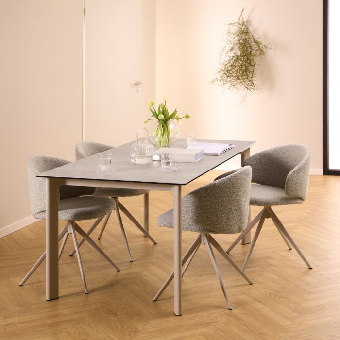 Dining table set with four chairs in a room with wooden flooring and a plant on the wall.