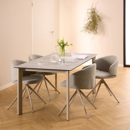 Dining table set with four chairs in a room with wooden flooring and a plant on the wall.