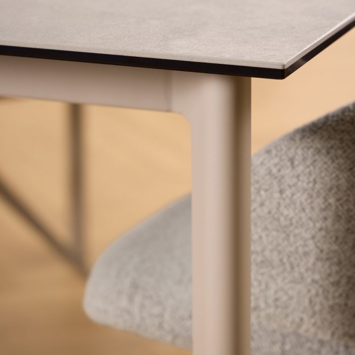 Close-up of a modern table with a beige base and gray top, blurred chair in the foreground.