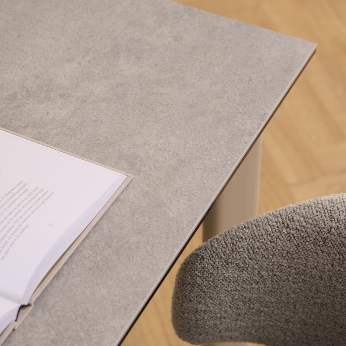 Gray office chair next to a desk with an open book on a wooden floor.