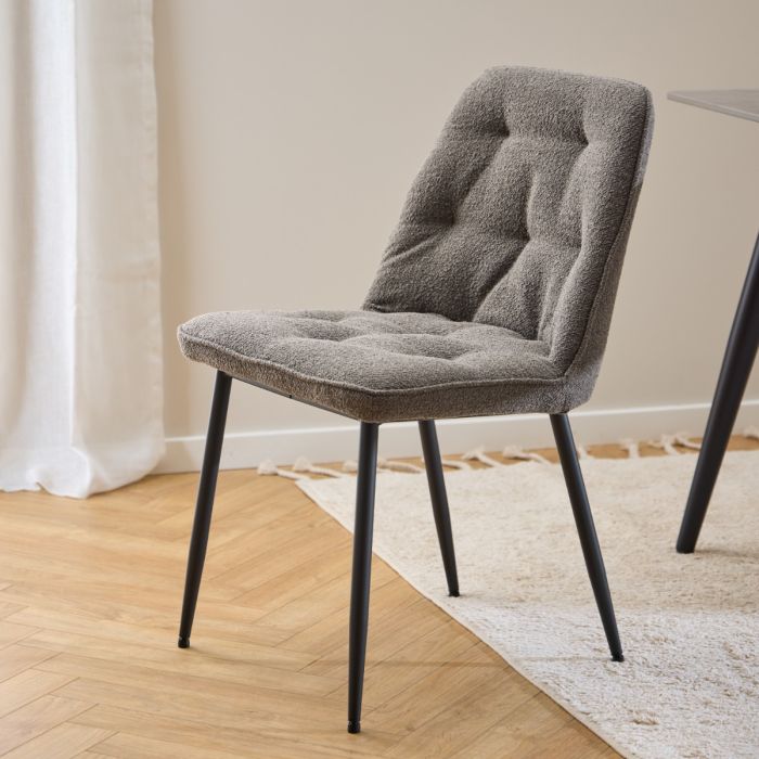 Gray upholstered chair with black legs on a wooden floor.