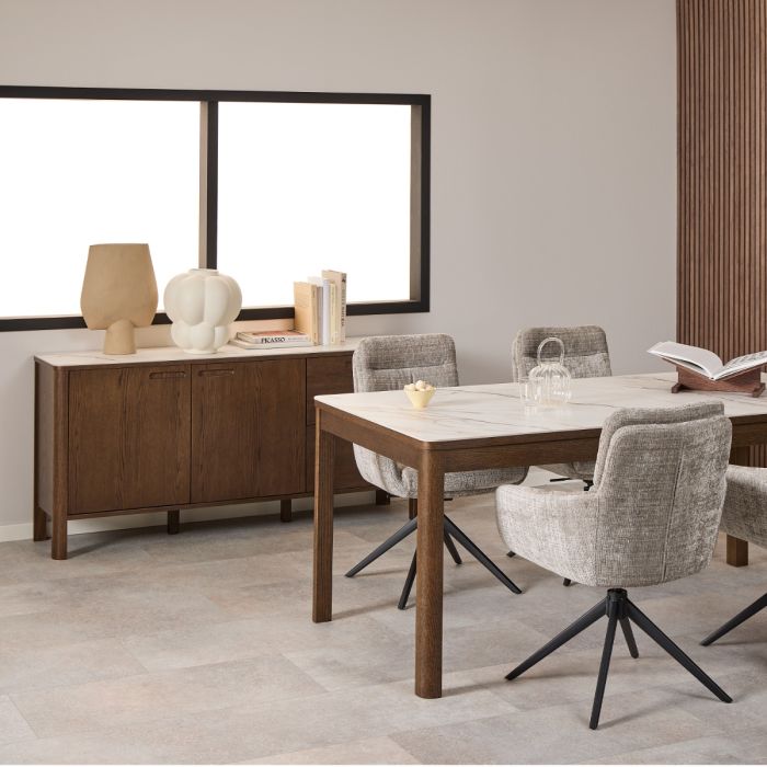 Dining room with wooden table, chairs, and sideboard against a neutral wall.