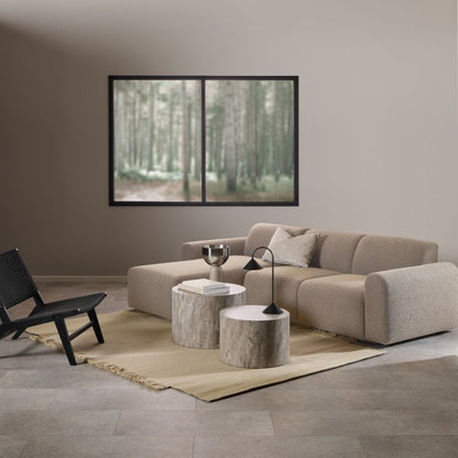 Modern living room with beige sectional sofa, black chair, and abstract art on wall.