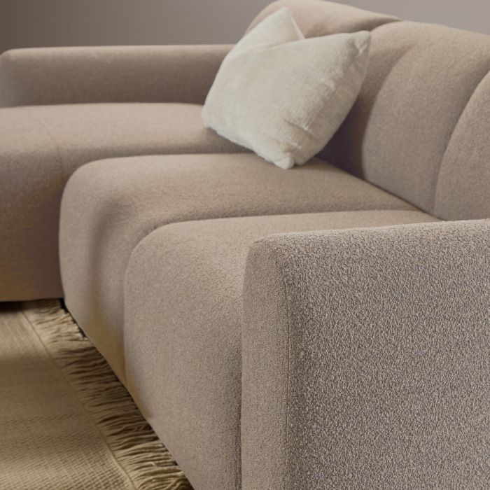 Beige sofa with a textured surface and a pillow on a neutral background