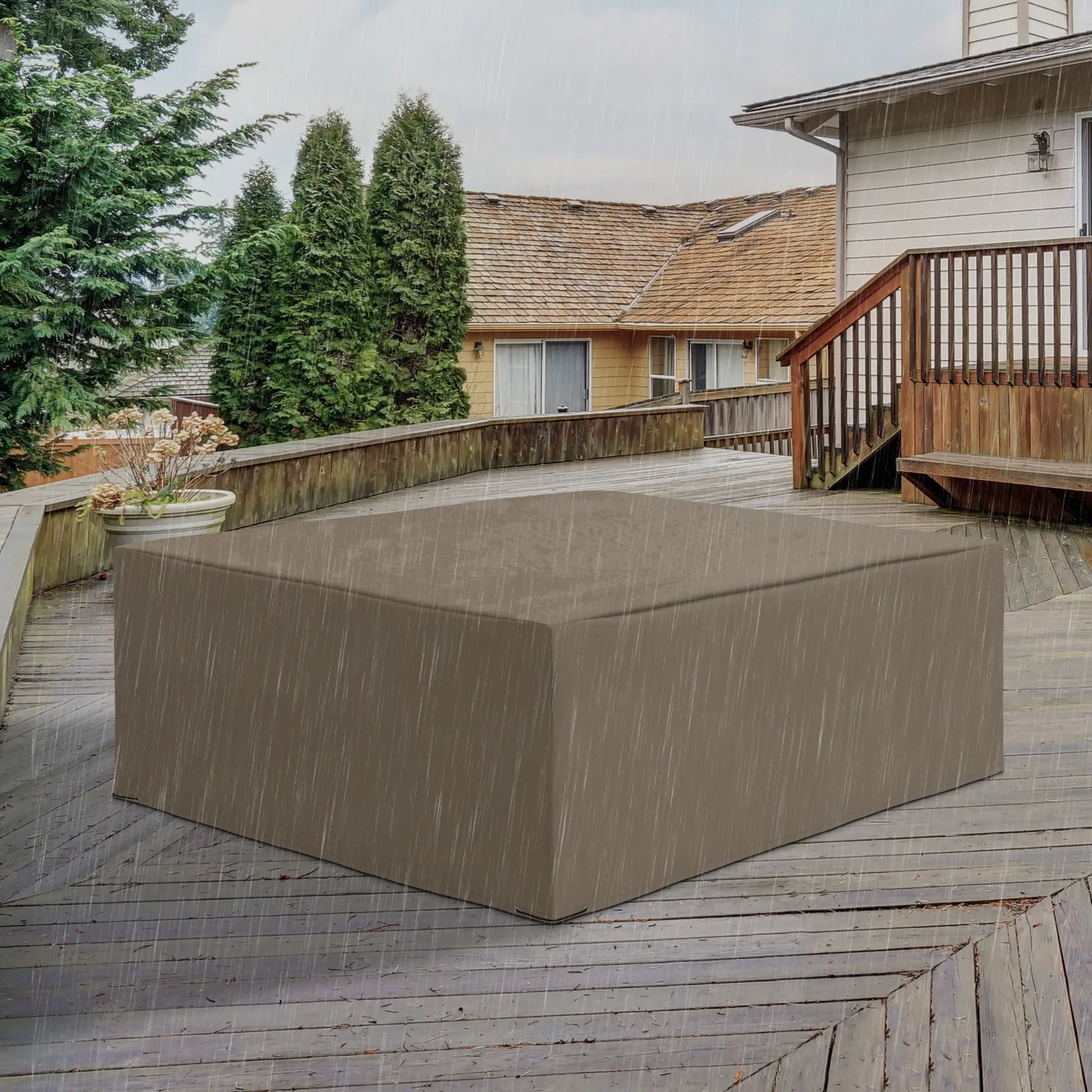 Brown rectangular outdoor furniture cover on a wooden deck with a house and trees in the background