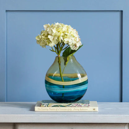 Decorative vase with flowers on a shelf against a blue wall