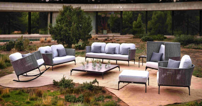Outdoor patio furniture set with chairs, sofa, and ottoman in a garden setting.