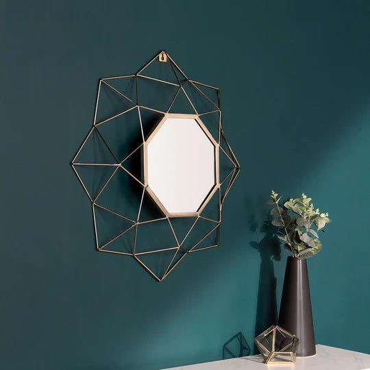 Geometric wall mirror with gold frame on a teal wall