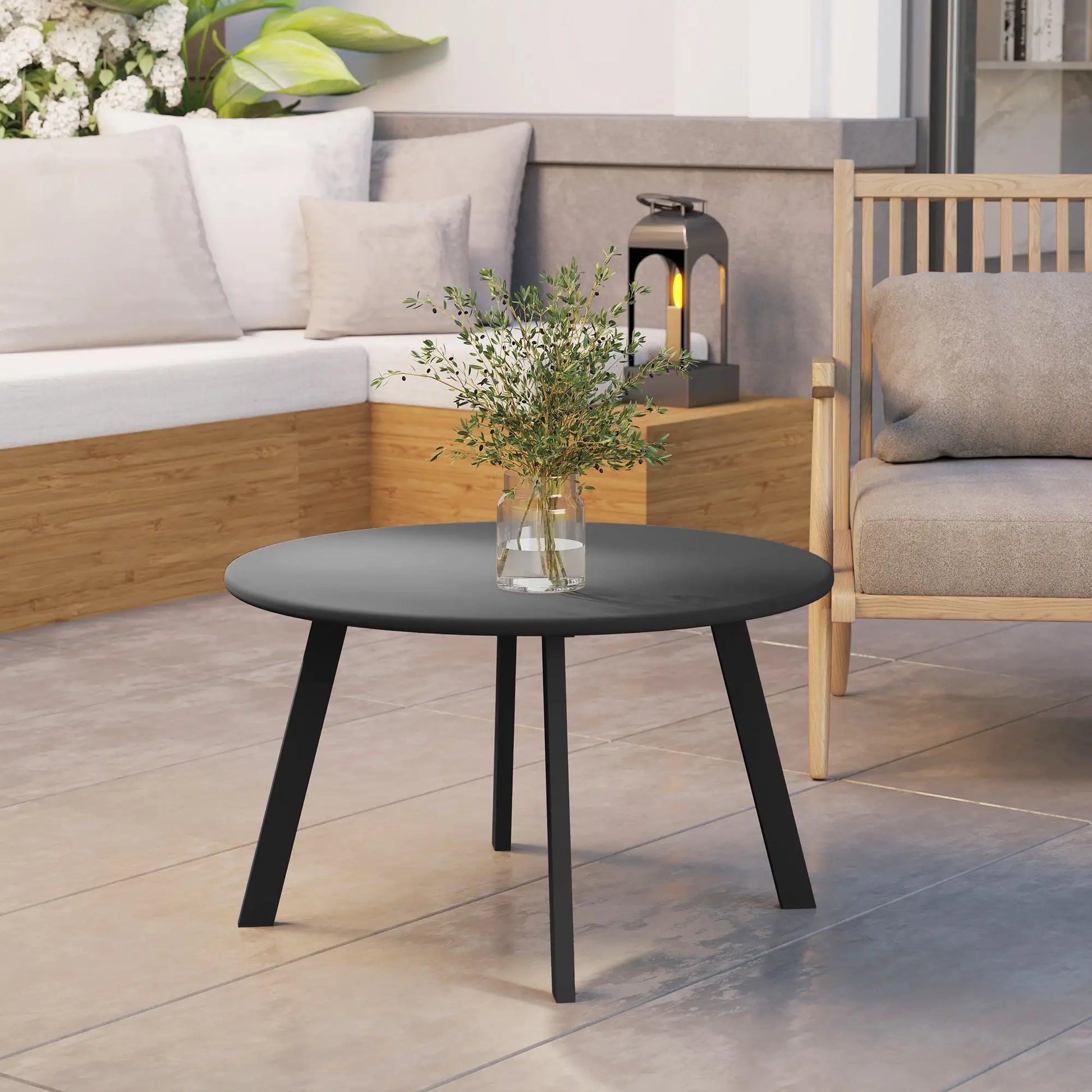 Round black coffee table with a vase of flowers in an outdoor setting