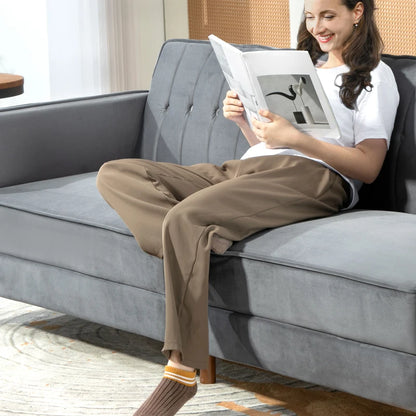 Woman sitting on a gray sofa reading a magazine in a living room.