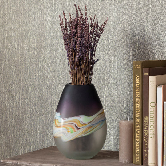 Decorative vase with marbled design and dried lavender on a shelf with books and a candle.
