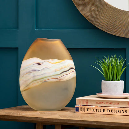 Decorative vase on a wooden surface with a teal wall and books in the background