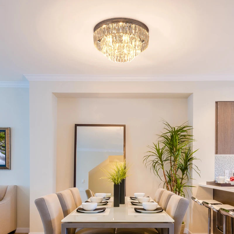 Dining room with a crystal chandelier, table set for dinner, and decorative plants.
