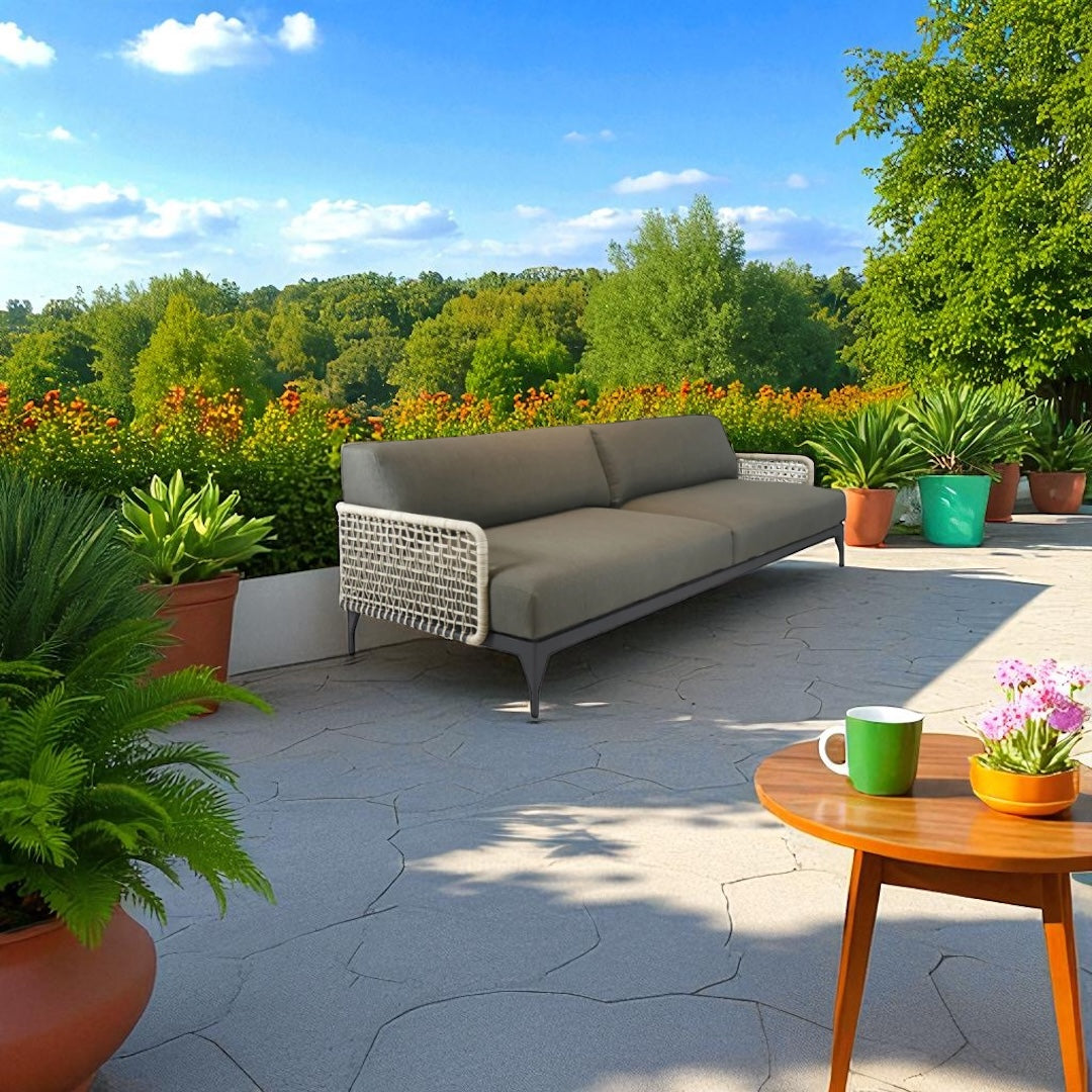Outdoor patio with a gray sofa, wooden table, and potted plants on a sunny day.