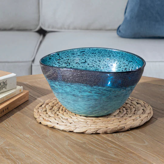 Blue glass bowl on a woven placemat with a couch in the background