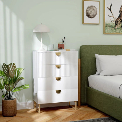 White dresser with gold accents next to a green bed in a room with light green walls.