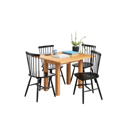 Wooden dining table with four black chairs on a white background