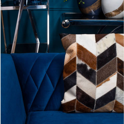 Blue armchair with a patterned pillow against a blue wall