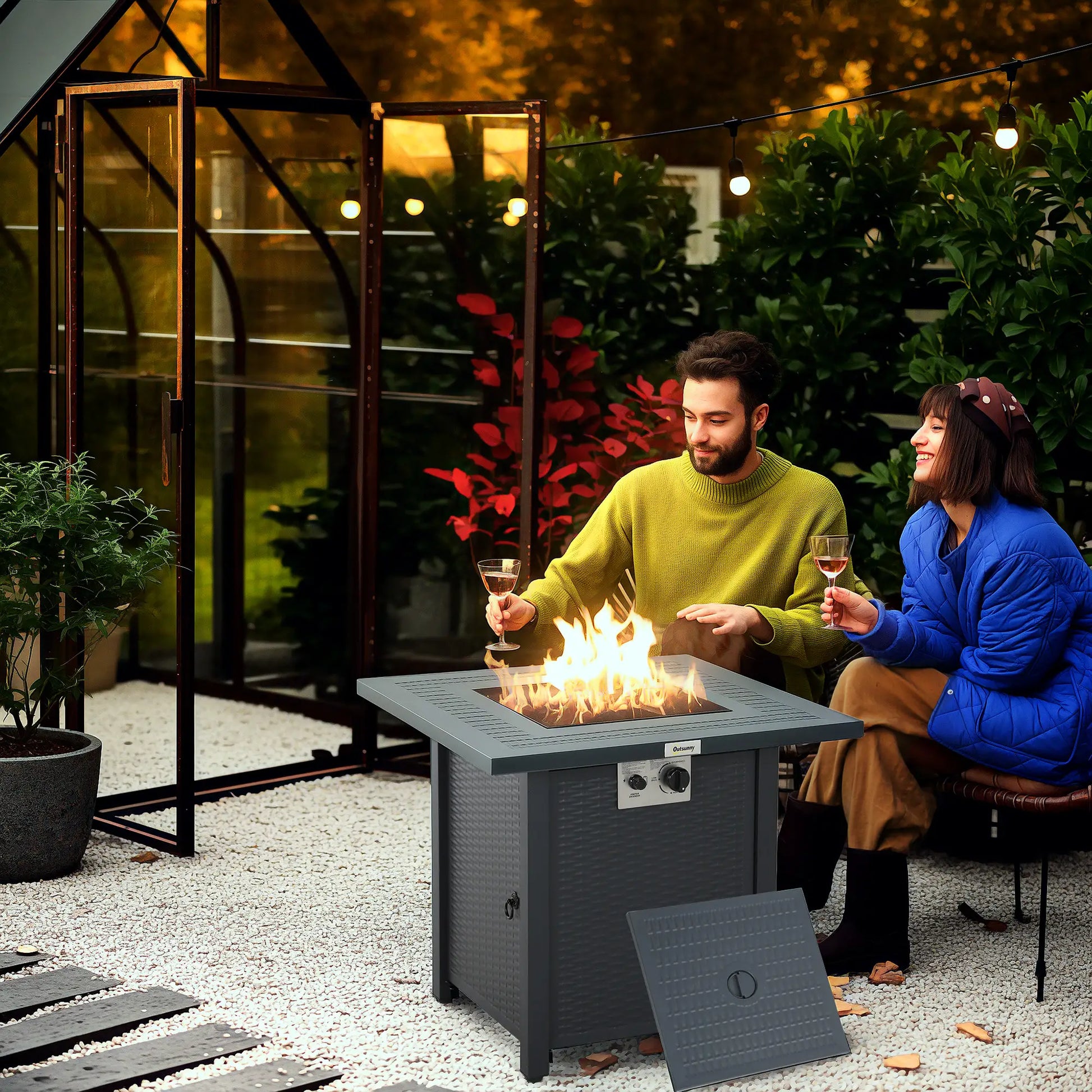 Two people sitting around a fire pit table in an outdoor setting.