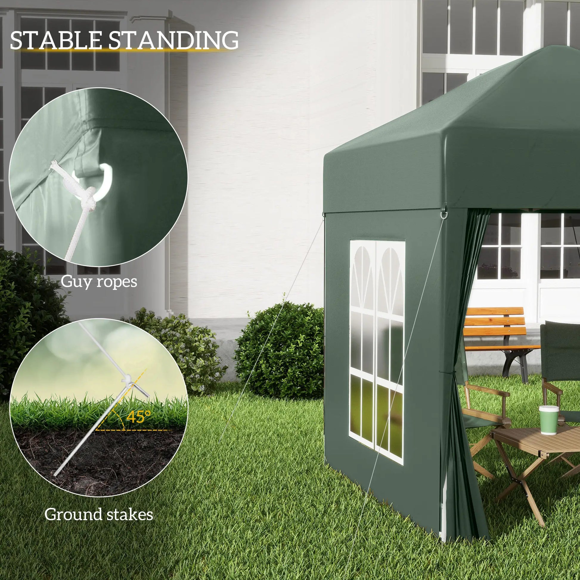 Green outdoor canopy tent with guy ropes and ground stakes, set up on grass with a bench and table in the background.