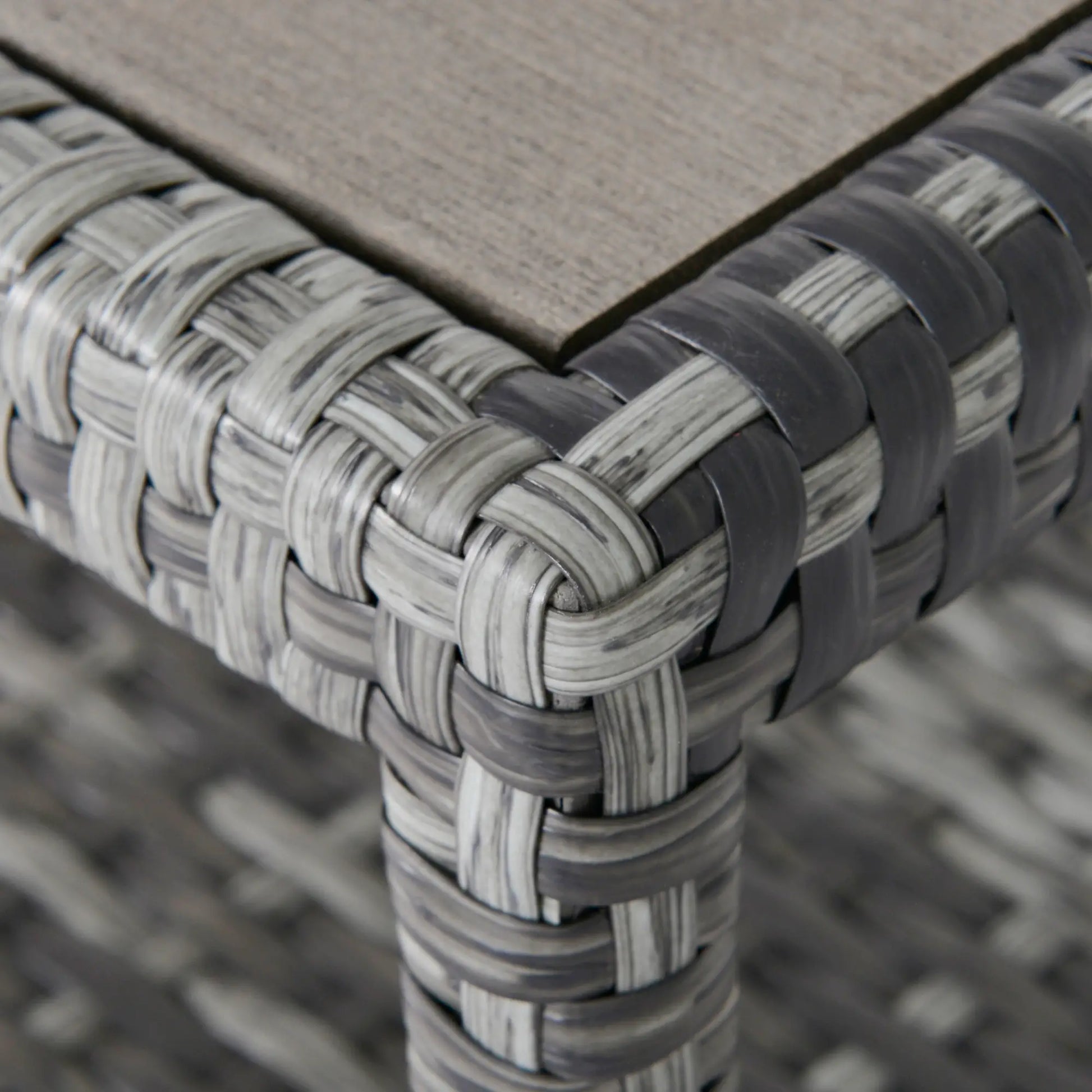 Close-up of a woven chair corner with a wooden seat.