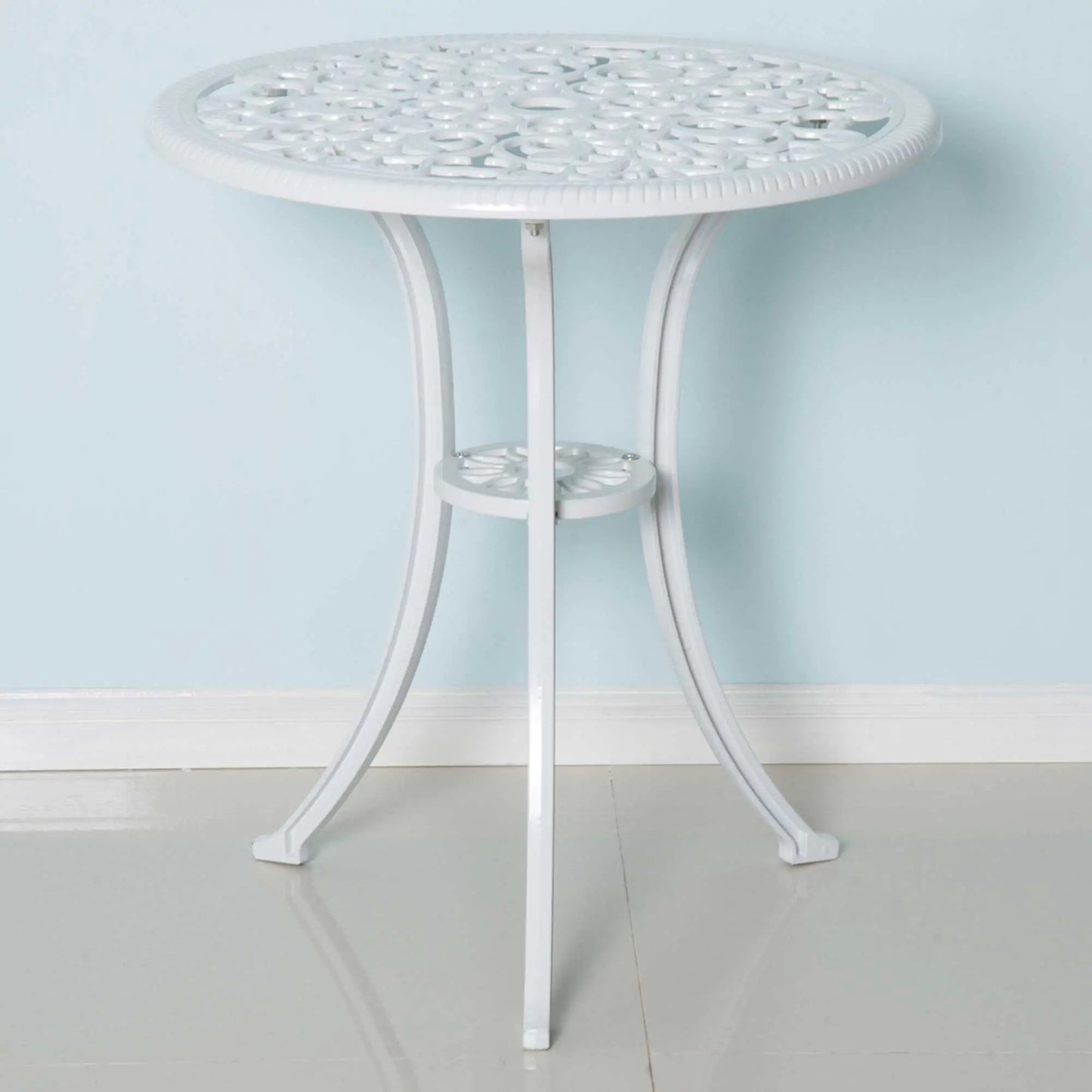 Round white metal table with decorative top against a light blue wall.