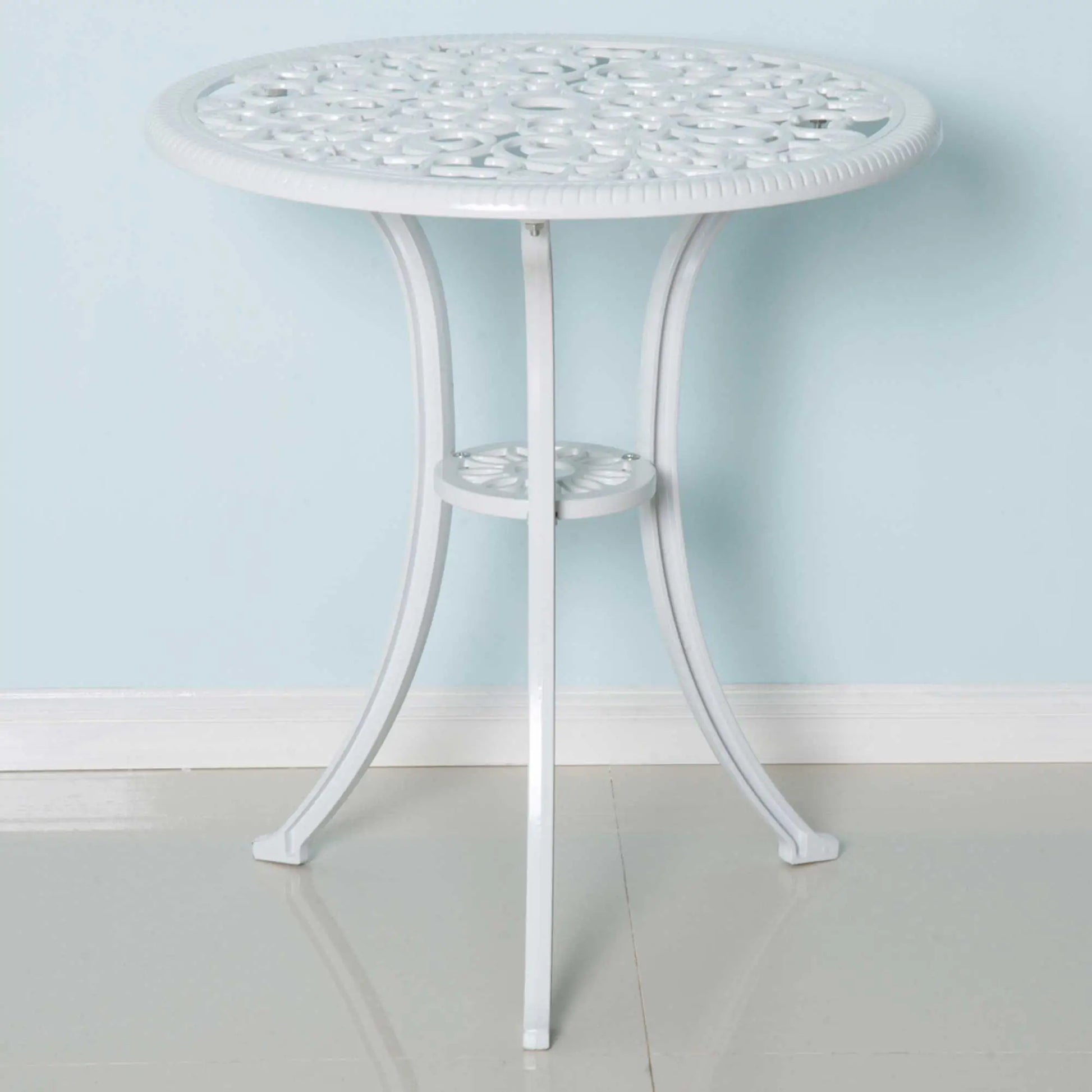Round white metal table with decorative top against a light blue wall.