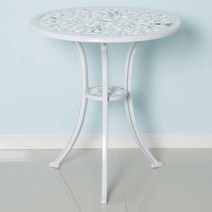 Round white metal table with decorative top against a light blue wall.