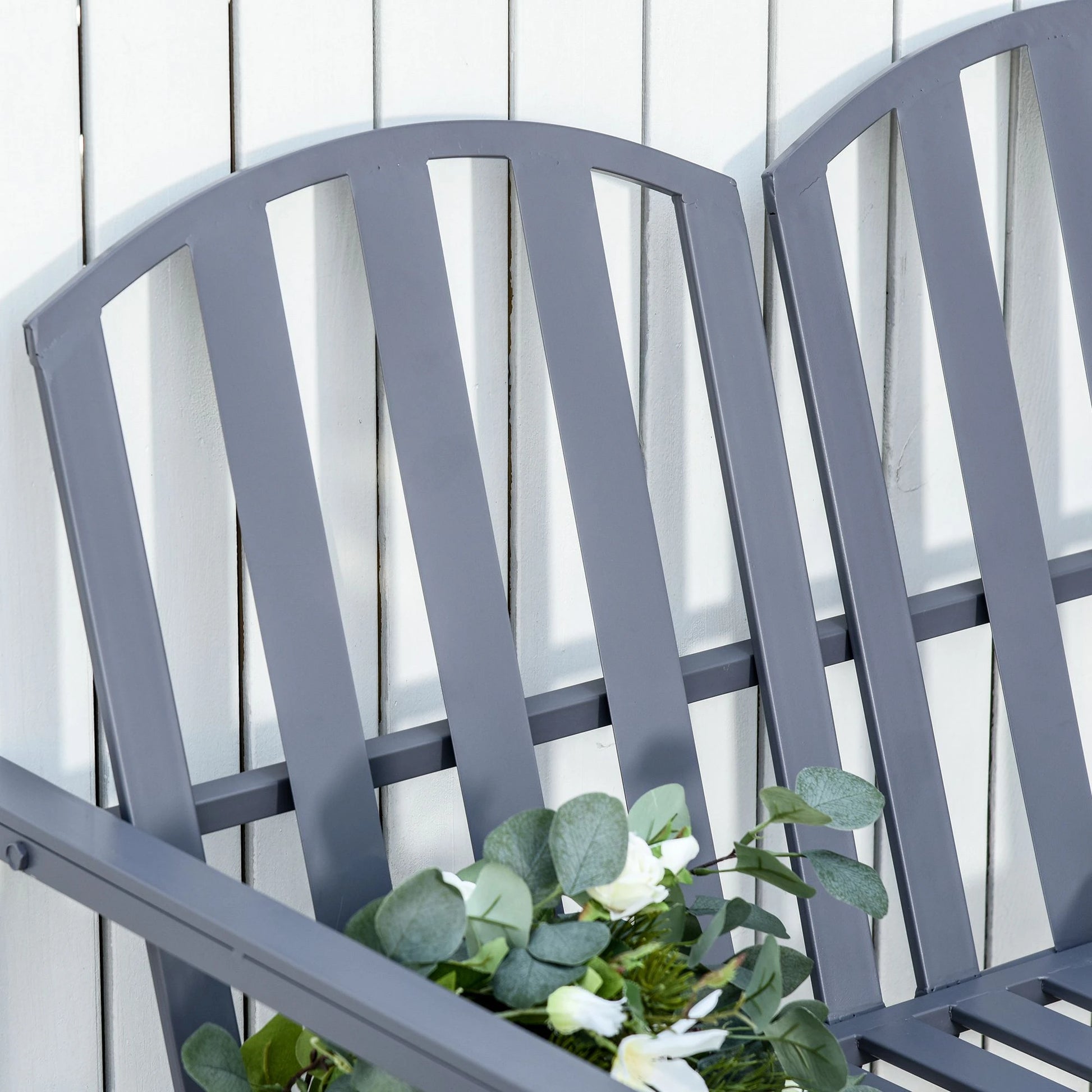 Gray metal bench with a white flower arrangement against a light wooden panel background