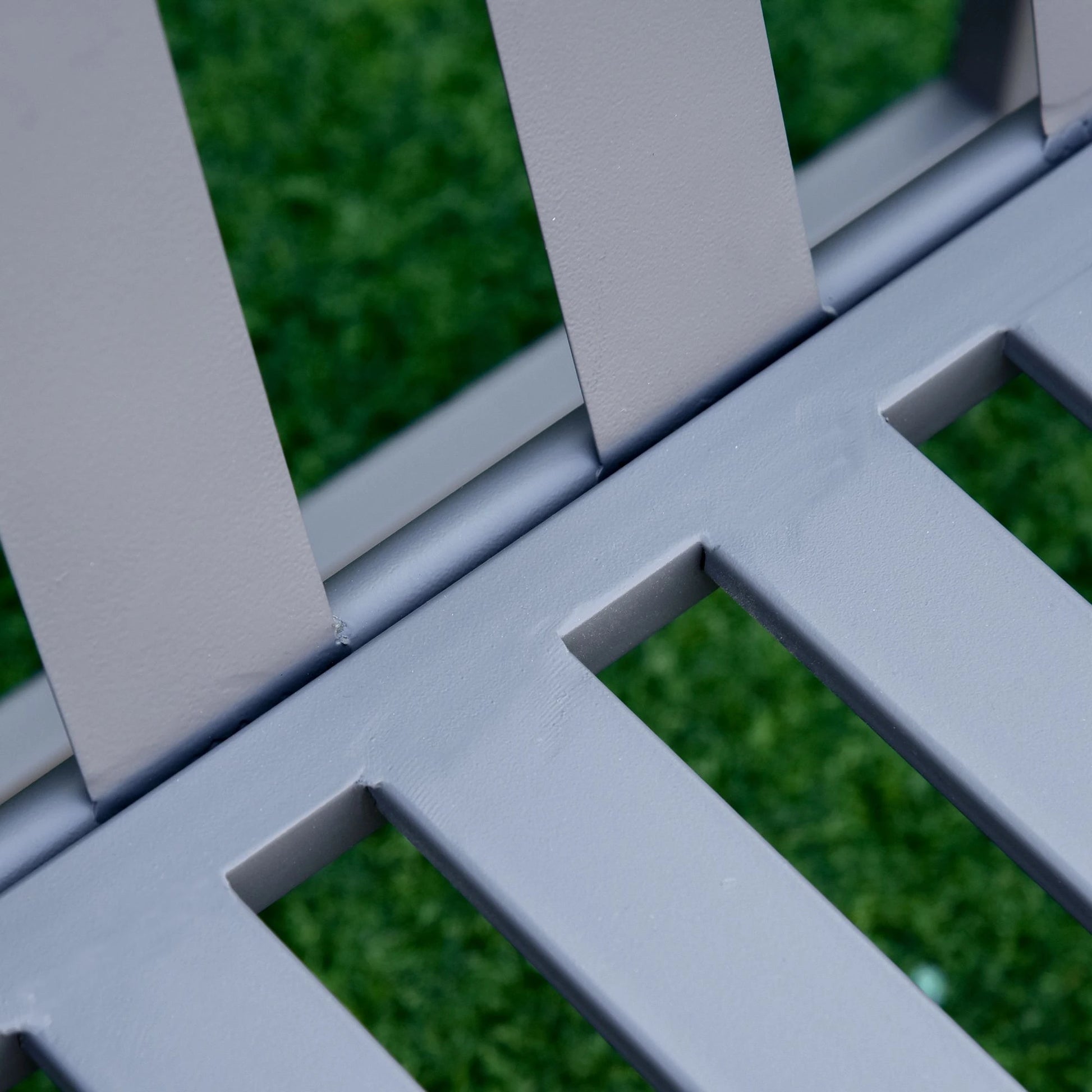 Close-up of a metal grid with green grass in the background