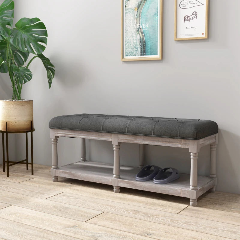 Gray cushioned bench with shoe storage on a wooden floor, plant and wall art in the background.