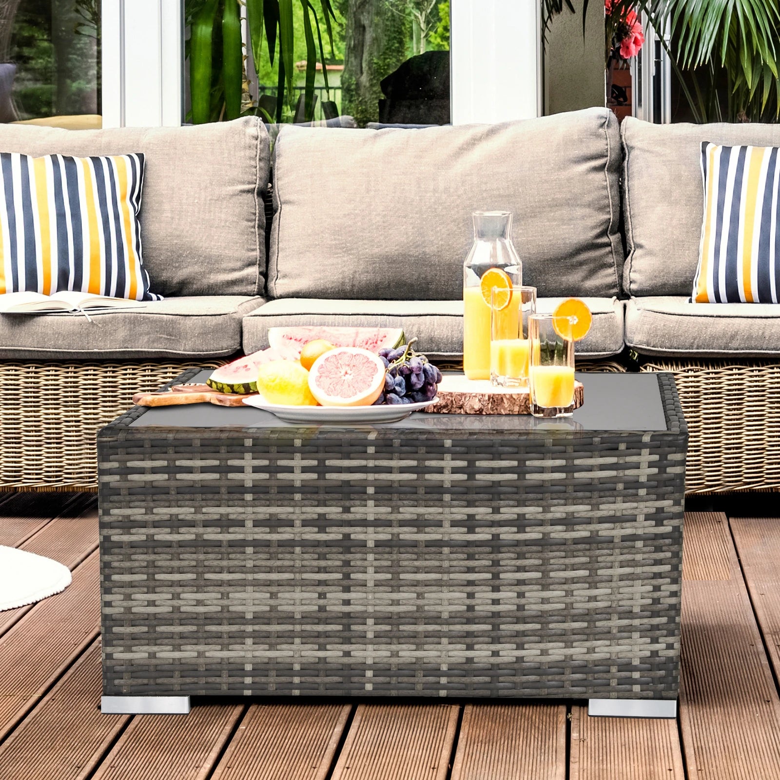 Outdoor patio set with a coffee table, cushions, and fruit on a wooden deck.