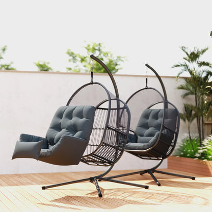 Two hanging egg chairs with gray cushions on a wooden deck with plants in the background.