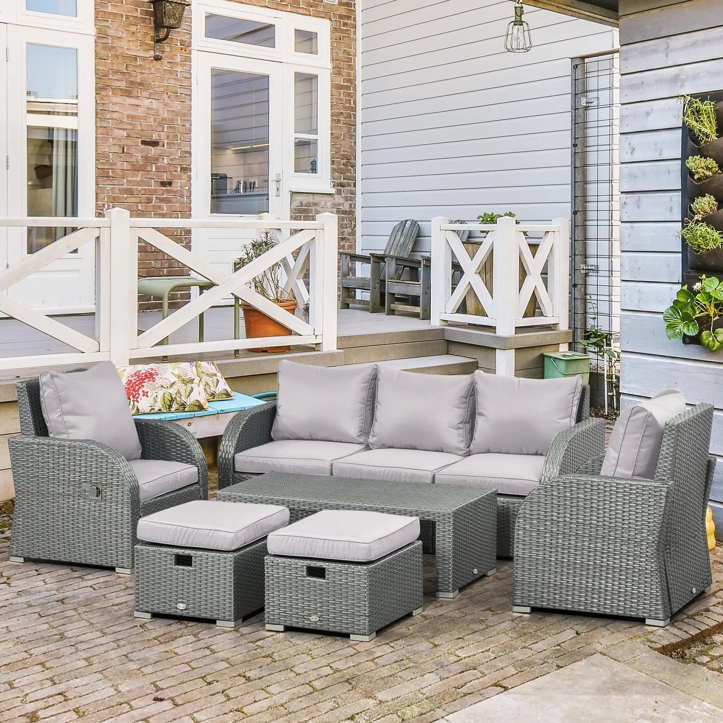 Gray outdoor furniture set with cushions on a patio in front of a house.