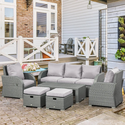 Gray outdoor furniture set with cushions on a patio in front of a house.