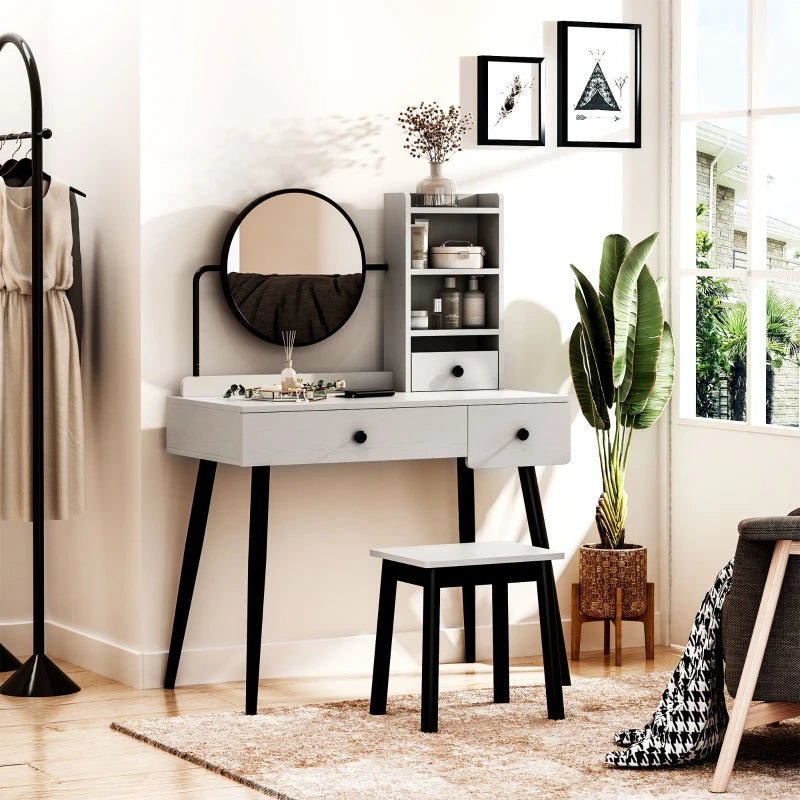 White vanity table with black legs in a room with a plant and coat rack.