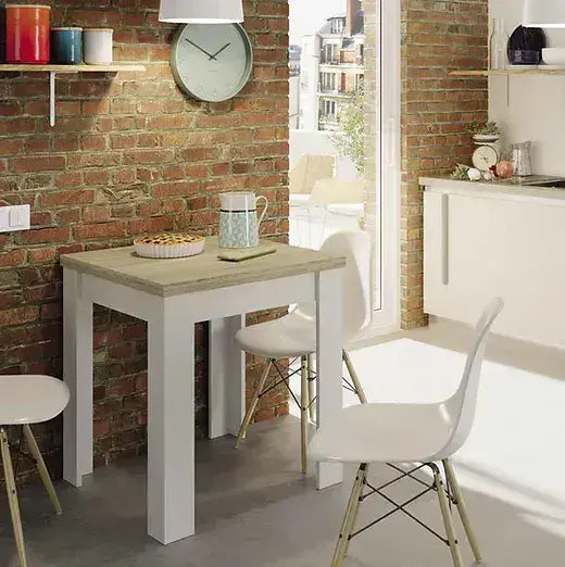 Small dining area with a white table and chairs against a brick wall.