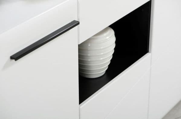 White vase inside a black-framed cabinet with a black handle.