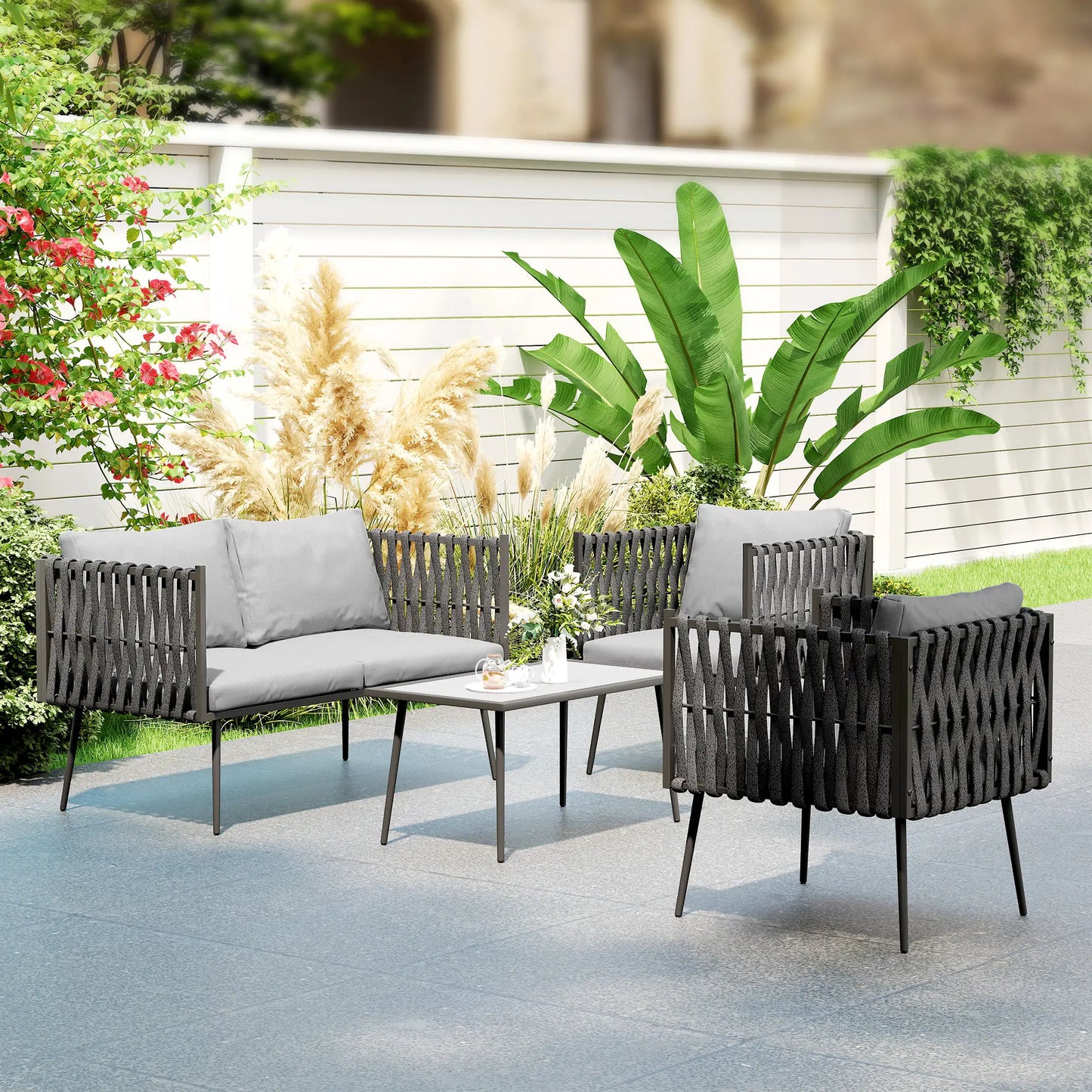 Outdoor patio set with gray cushions and a small table in a garden setting.